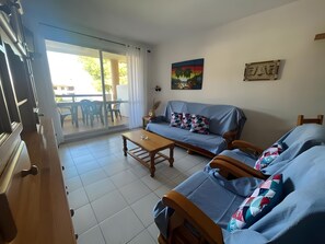 Sala de estar com sofá, mesa de centro e área de jantar com cadeiras e mesa.