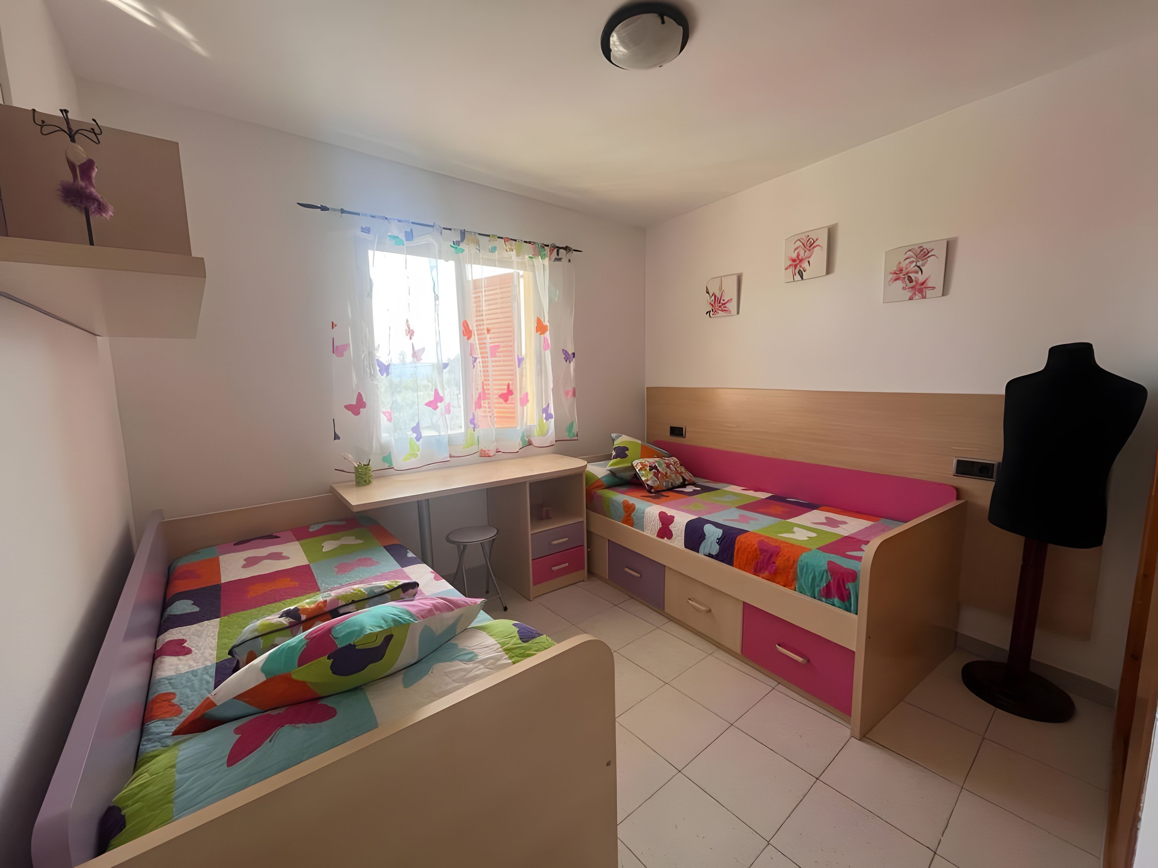 Una habitación con dos camas, un escritorio, una silla y un maniquí.