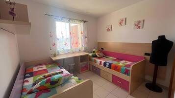 Una habitación con dos camas, un escritorio, una silla y un maniquí.