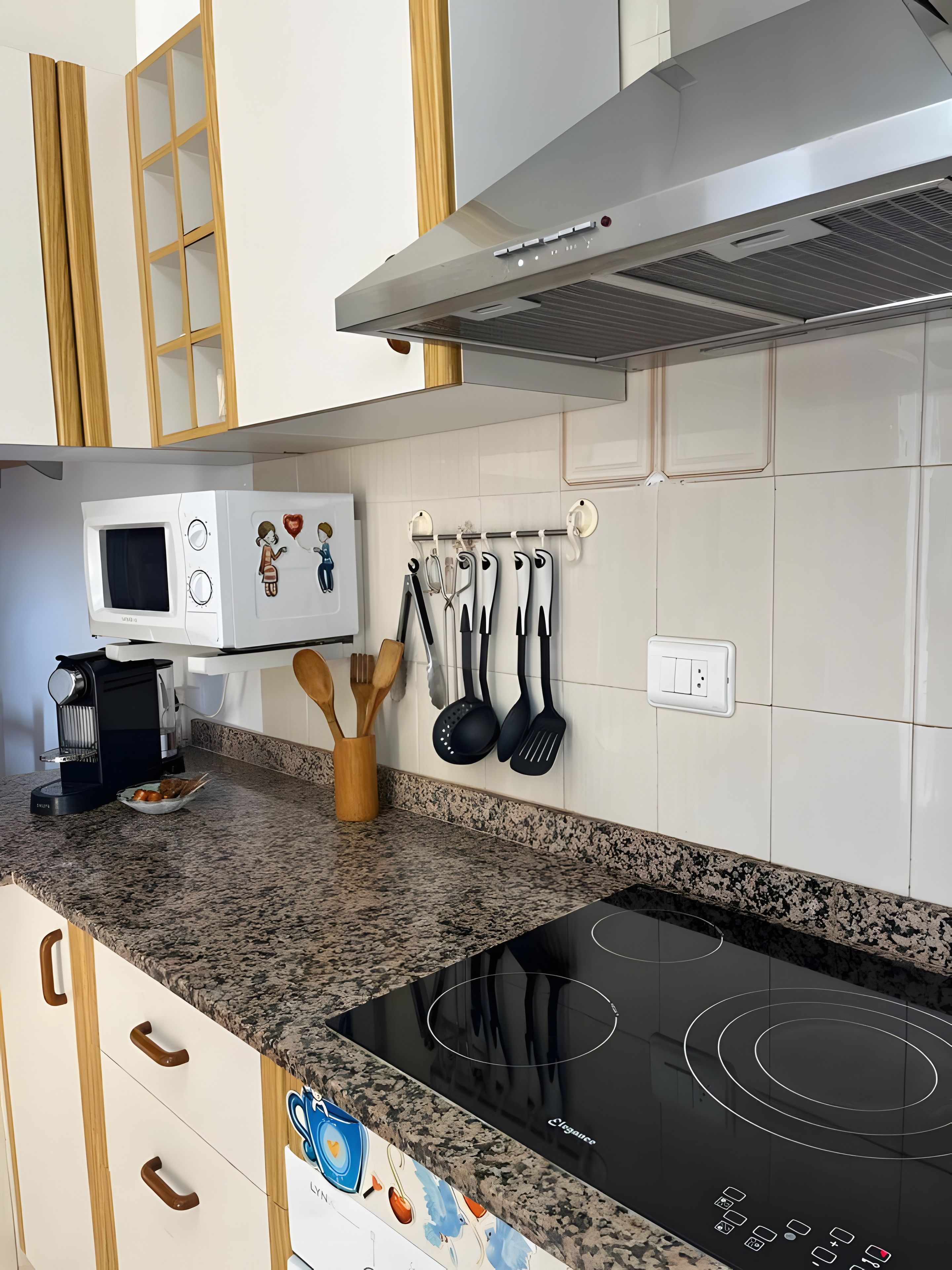 Een keuken met een ingebouwde magnetron, een kookplaat en een wandbeugel voor keukengerei.