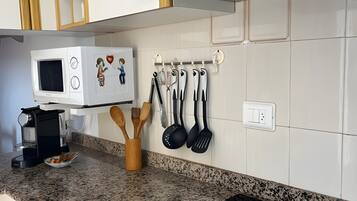 Een keuken met een ingebouwde magnetron, een kookplaat en een wandbeugel voor keukengerei.