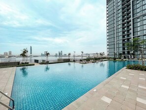 A swimming pool with a view of a city skyline, surrounded by a modern building. - Chic 1BR Escape in Creek Edge | Creek Harbour (Dubai)