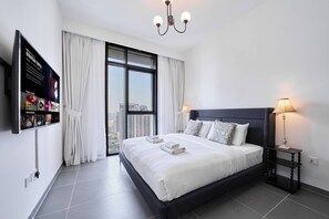 A modern hotel room with a large bed, a TV mounted on the wall, and a view of the city through the window. - Chic 1BR Escape in Creek Edge | Creek Harbour (Dubai)