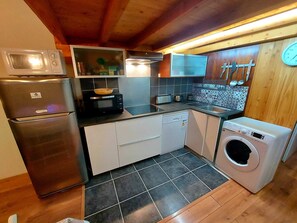 Eine kompakte Küche mit Kühlschrank, Mikrowelle, Toaster und Waschmaschine.