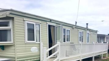 A row of mobile homes with white railings and a small porch area.