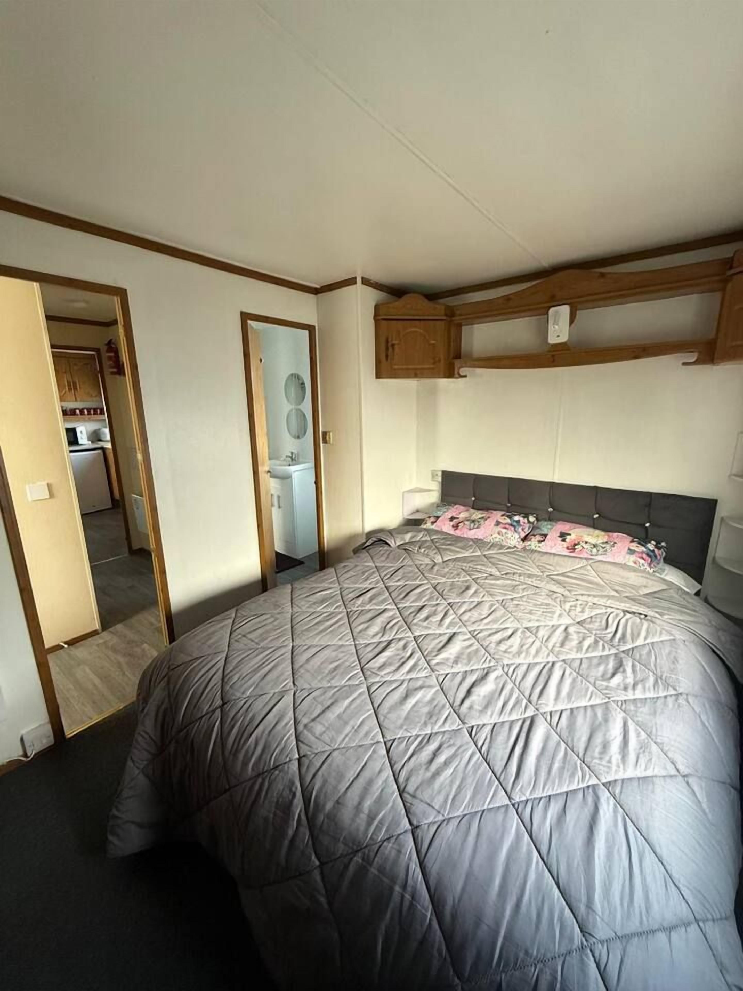A bedroom with a large bed, a built-in wardrobe, and a small kitchenette.