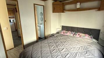 A bedroom with a large bed, a built-in wardrobe, and a small kitchenette.