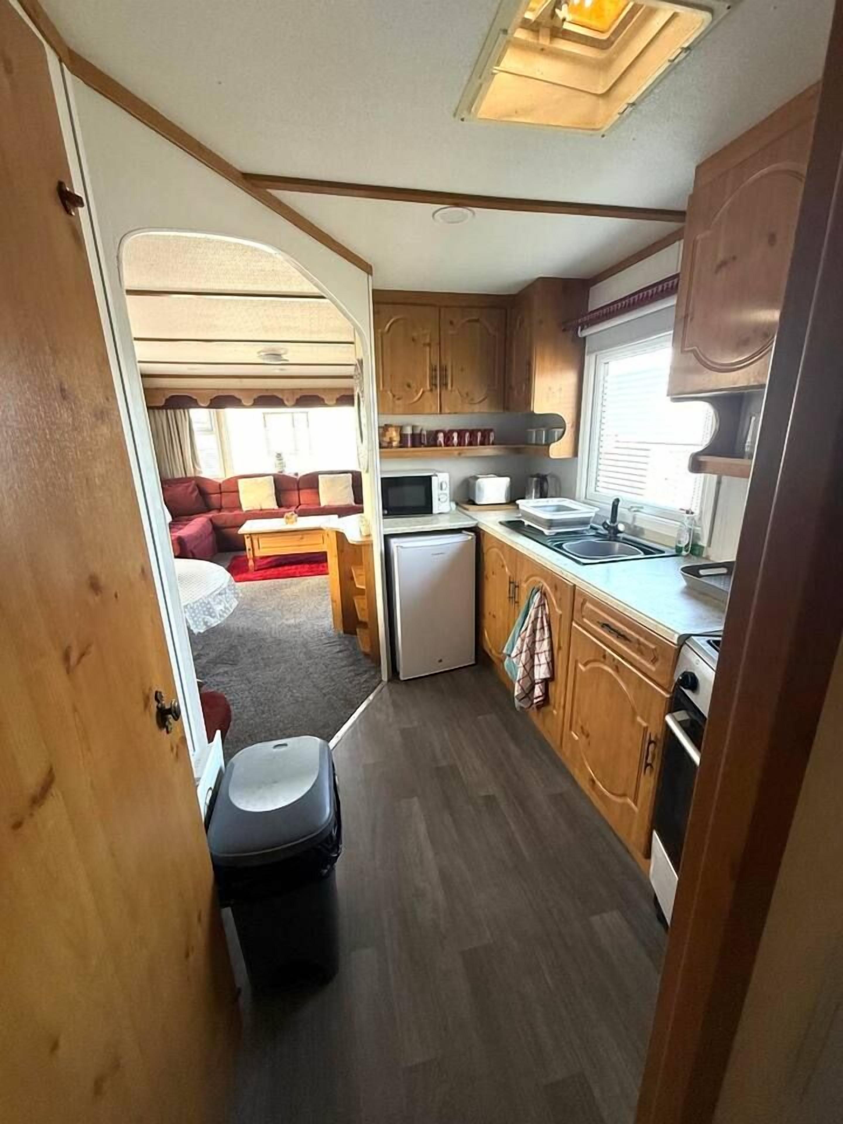 A compact RV kitchen with a refrigerator, microwave, sink, and stove.