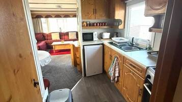 A compact RV kitchen with a refrigerator, microwave, sink, and stove.