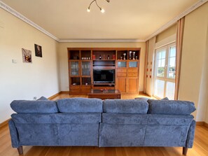 Ein Wohnzimmer mit einem großen blauen Sofa, einer Holztv-Möbel und einem Fernseher.