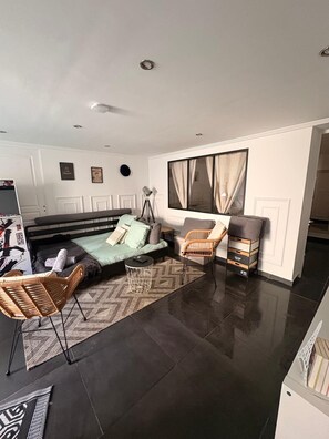 A modern living room with a sofa, two chairs, a coffee table, and a side table. - Vrbo Property (Serris)