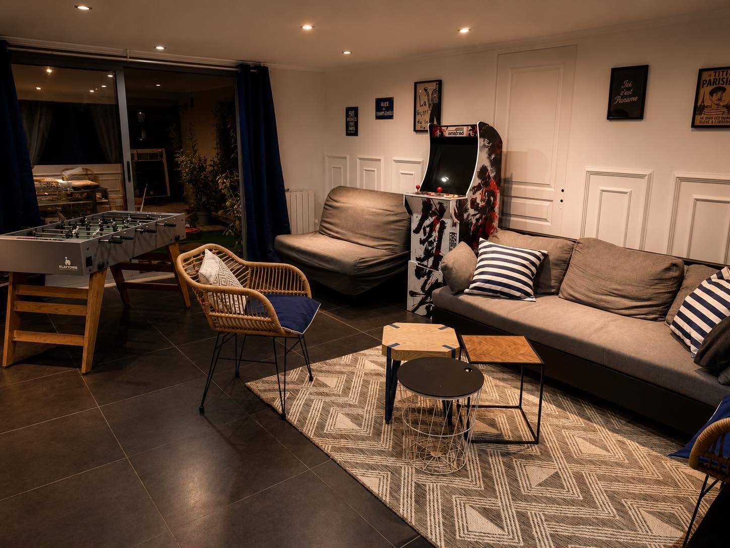 A living room with a foosball table, a sofa, a chair, and a small coffee table.