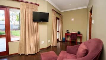 Una habitación con un televisor de pantalla plana montado en la pared, un sillón rojo y una pequeña mesa con una silla.