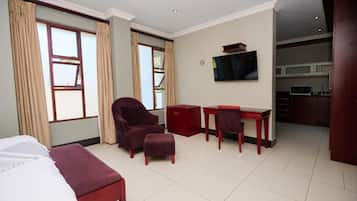 Una habitación de hotel con cama, escritorio, silla y televisor.