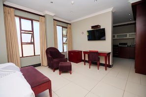 Una habitación de hotel con cama, escritorio, silla y televisor.