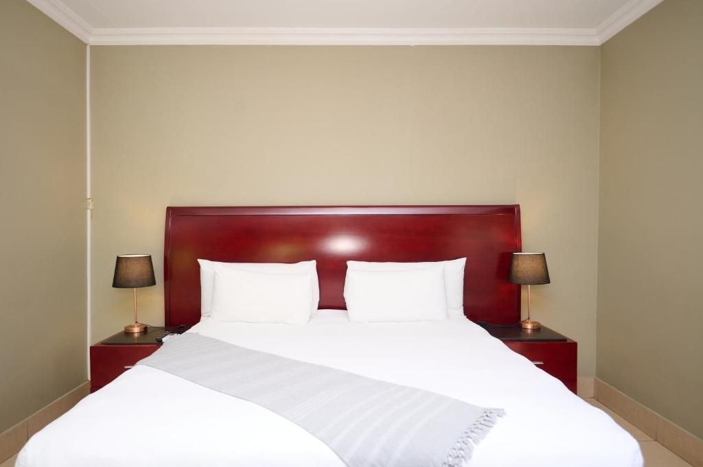 Habitación de hotel con una cama grande, dos mesitas de noche y lámparas.