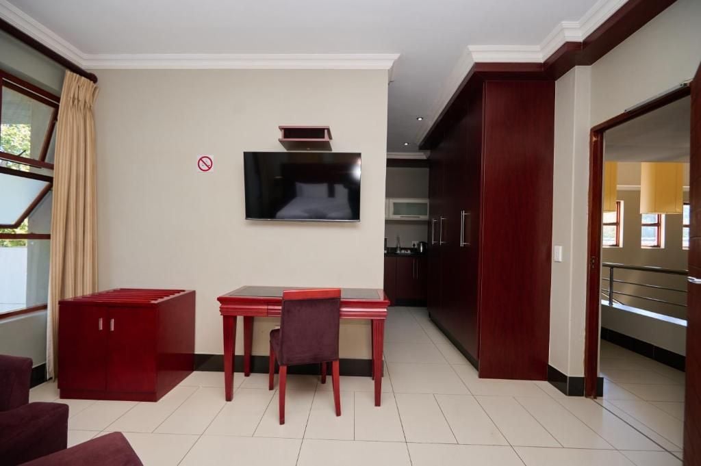 Habitación de hotel moderna con zona de comedor, televisor de pantalla plana en la pared y vistas al exterior a través de una ventana.