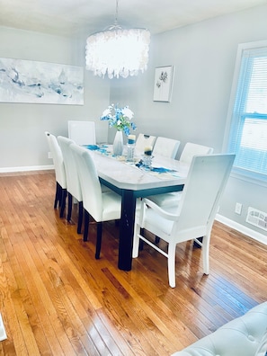 A dining room with a white table, chairs, a chandelier, and artwork on the walls. -  4-bedroom house in Saint Paul (Saint Paul)