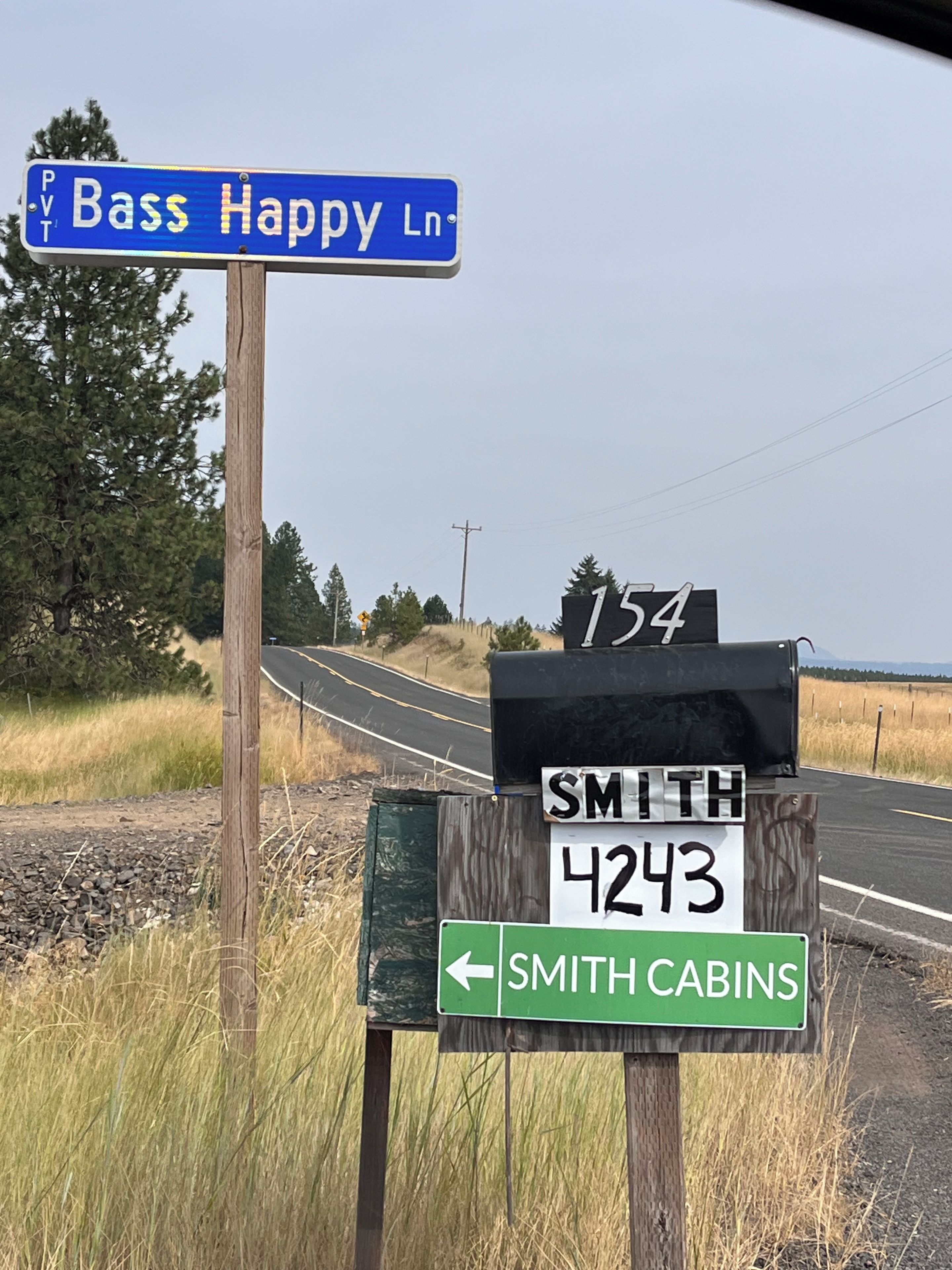 Road signs indicating directions to Bass Happy Ln, Smith 4243, and Smith Cabins.