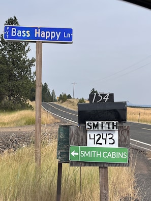 Road signs indicating directions to Bass Happy Ln, Smith 4243, and Smith Cabins.