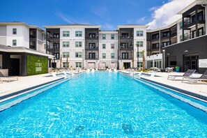 A swimming pool with a clear blue water surface, surrounded by a modern building with multiple balconies and a green wall. - Landing Spectacular 1BD in Clara Avenue (Panama City Beach)