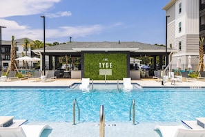A swimming pool with lounge chairs, a covered seating area, and a sign reading 'THE TYDE.' - Landing Spectacular 1BD in Clara Avenue (Panama City Beach)