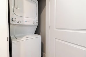 A white stacked washer and dryer unit with control knobs and a digital display. - Landing Spectacular 1BD in Clara Avenue (Panama City Beach)