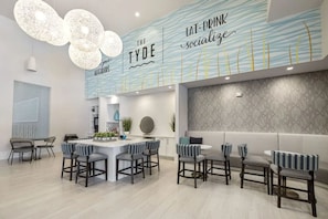 A modern kitchen with a central island, bar stools, pendant lighting, and a wall with 'The Tyde' branding. - Landing Spectacular 1BD in Clara Avenue (Panama City Beach)