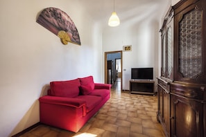 A living room with a red sofa, a television, and a wooden cabinet. - Borgo Tegolaio House by MMega (Firenze)