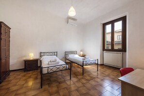 Une chambre avec deux lits, une armoire en bois, un radiateur et une fenêtre donnant sur un beau paysage.