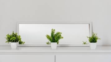 Une étagère blanche sur laquelle sont posées trois pots blancs contenant des plantes vertes.