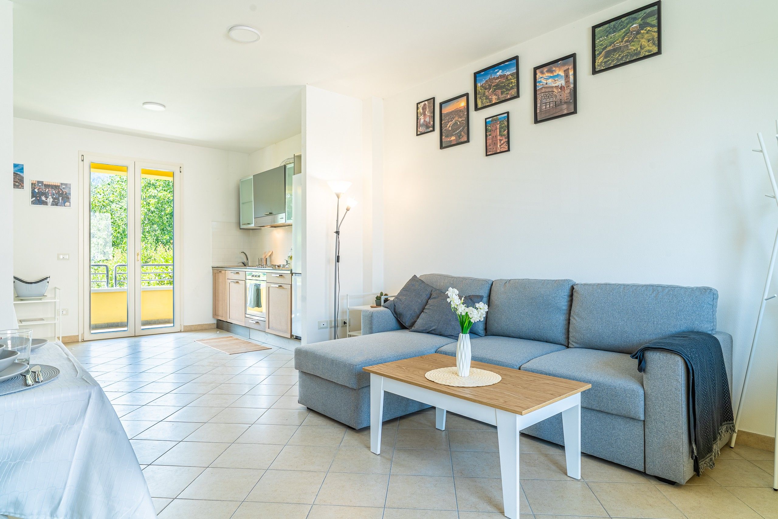 A modern living room with a grey sofa, a coffee table, and a kitchen in the background.