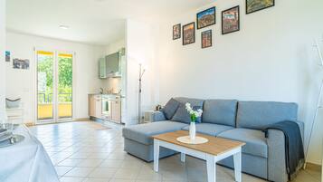 A modern living room with a grey sofa, a coffee table, and a kitchen in the background.