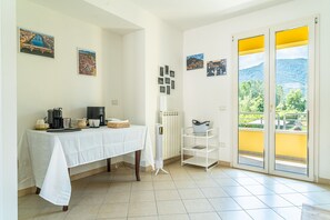 Une pièce avec une table préparée pour le petit-déjeuner, un radiateur et une vue sur la verdure grâce à une porte coulissante.