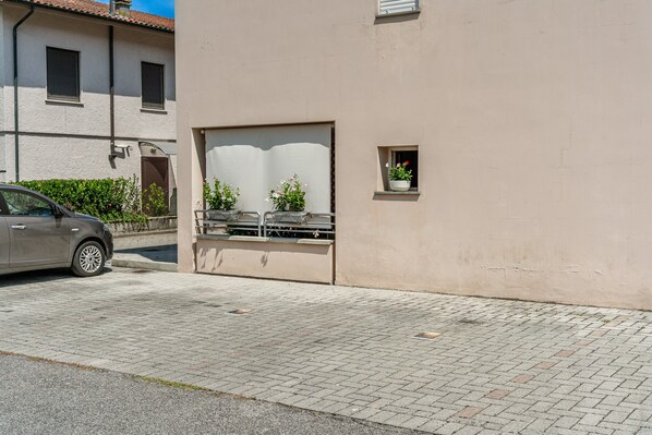 A building with a paved entrance, a car parked outside, and a small window with a potted plant. - Holiday Home 'Alba Sunrise - Ac Hot Tub Parking' with Wi-Fi and Air Conditioning (Lucca)