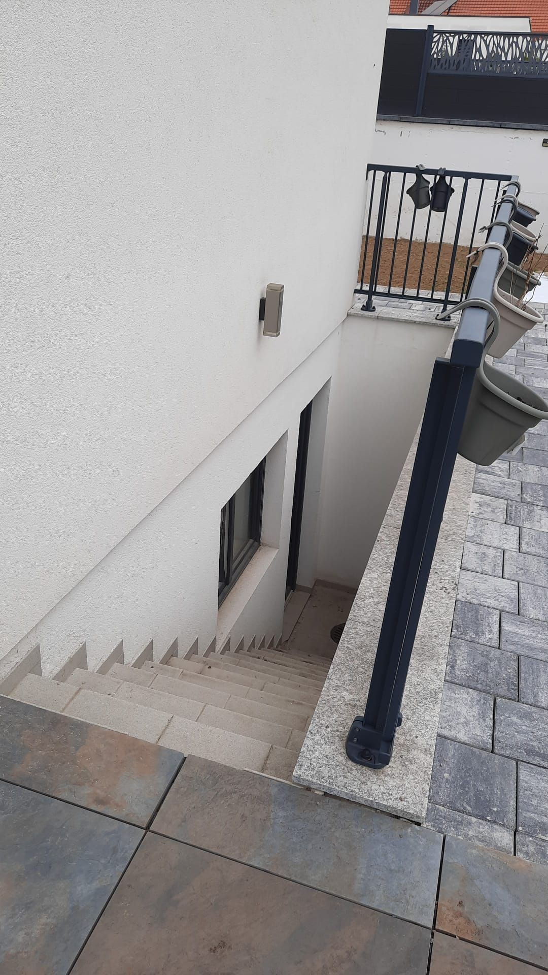 Una escalera que conduce a un balcón con barandilla de metal y una planta en maceta.
