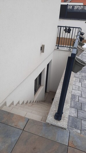Una escalera que conduce a un balcón con barandilla de metal y una planta en maceta.
