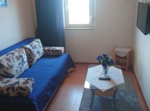 A room with a sofa, a small table with a vase, a chair, and a window. - Apartments Azuro (Dugi Rat)