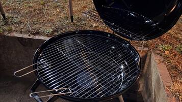 Ein schwarzer Grill mit Drahtrost, geöffnetem Deckel und einer kleinen Lampe am Boden.