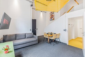 A modern interior with a grey sofa, a dining table with chairs, and a yellow accent wall. - One-Bedroom Apartment Near the Karmelitermarkt | Old Town Within Walking Distance (Wien)
