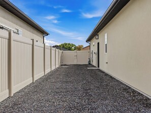 Un sendero que conduce a un edificio de fachada color beige y suelo de grava.
