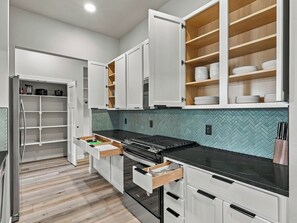 Eine moderne Küche mit weißen Schränken, einer schwarzen Arbeitsplatte und einer Küchenrückwand mit Fischgrätmuster.