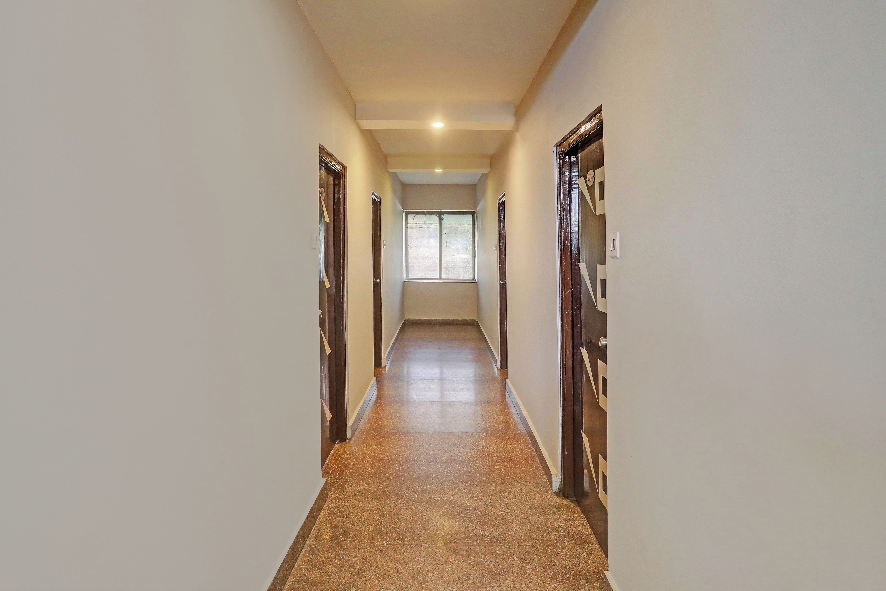 Un pasillo con piso de baldosas que conduce a una habitación con ventana.