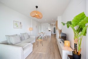 A modern living room with a sofa, dining table, and a large plant. - Casa Azahar · Beautiful apartment in Villamartín (Orihuela Costa)