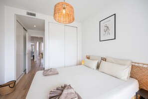 A bedroom with a large bed, a hanging light fixture, a framed artwork, and a wicker basket. - Casa Azahar · Beautiful apartment in Villamartín (Orihuela Costa)