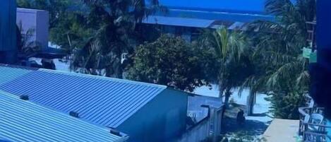 A view of a building with a blue roof, palm trees, and a clear sky.