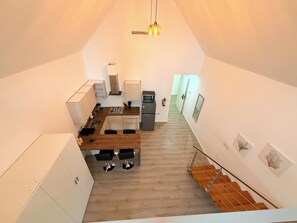 Eine kleine Küche mit Essbereich, einer Treppe und Blick zum Wohnraum.