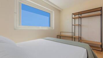 A bedroom with a bed, a window, a wardrobe, and a small table.