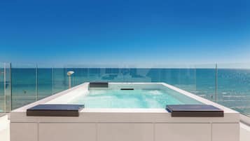 A rectangular hot tub with a clear view of the ocean and a clear sky.