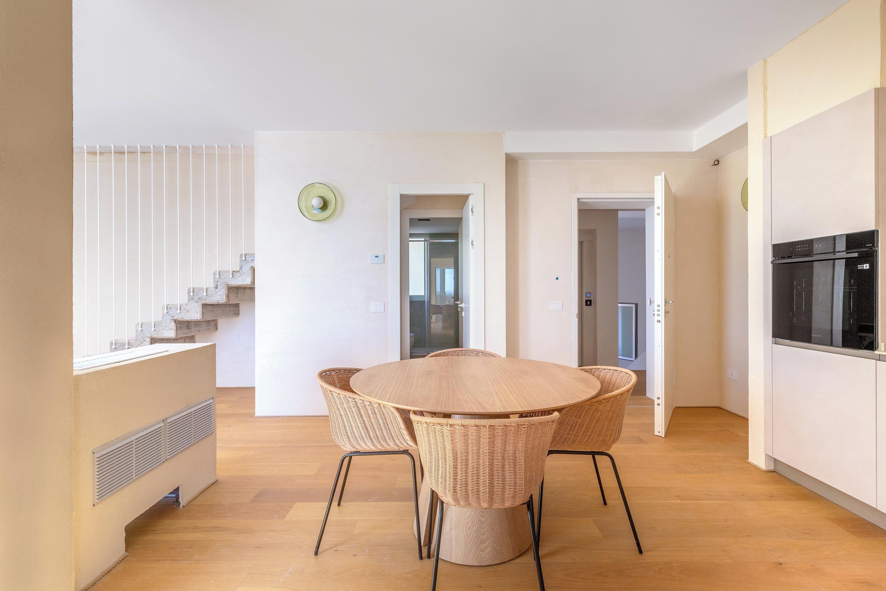 Una cucina moderna con un frigorifero nero e un'area pranzo con un tavolo rotondo in legno e sedie in vimini.